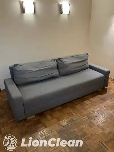 Sivi trosed sa dva velika jastuka za naslon ispod zidnih lampi