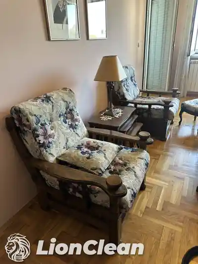 Fotelja sa cvetnom presvlakom i tamnim drvenim okvirom pored ogledala